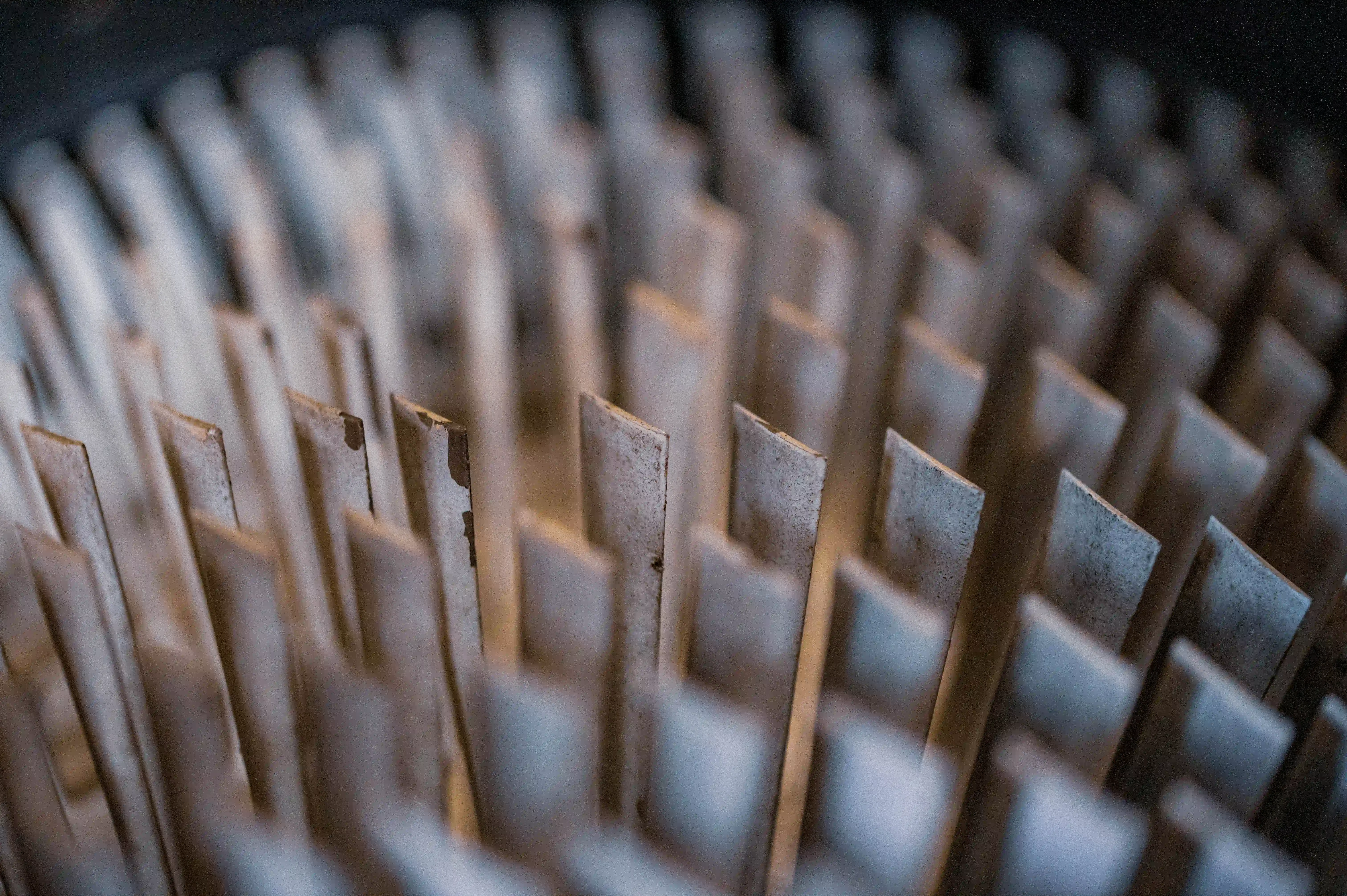 A shallow depth of field photograph showing a close-up of the fins of a jet engine turbine. The blades are arranged in a radial pattern, with some in sharp focus and others progressively blurred. The metallic surface of the blades shows a slightly worn texture.
