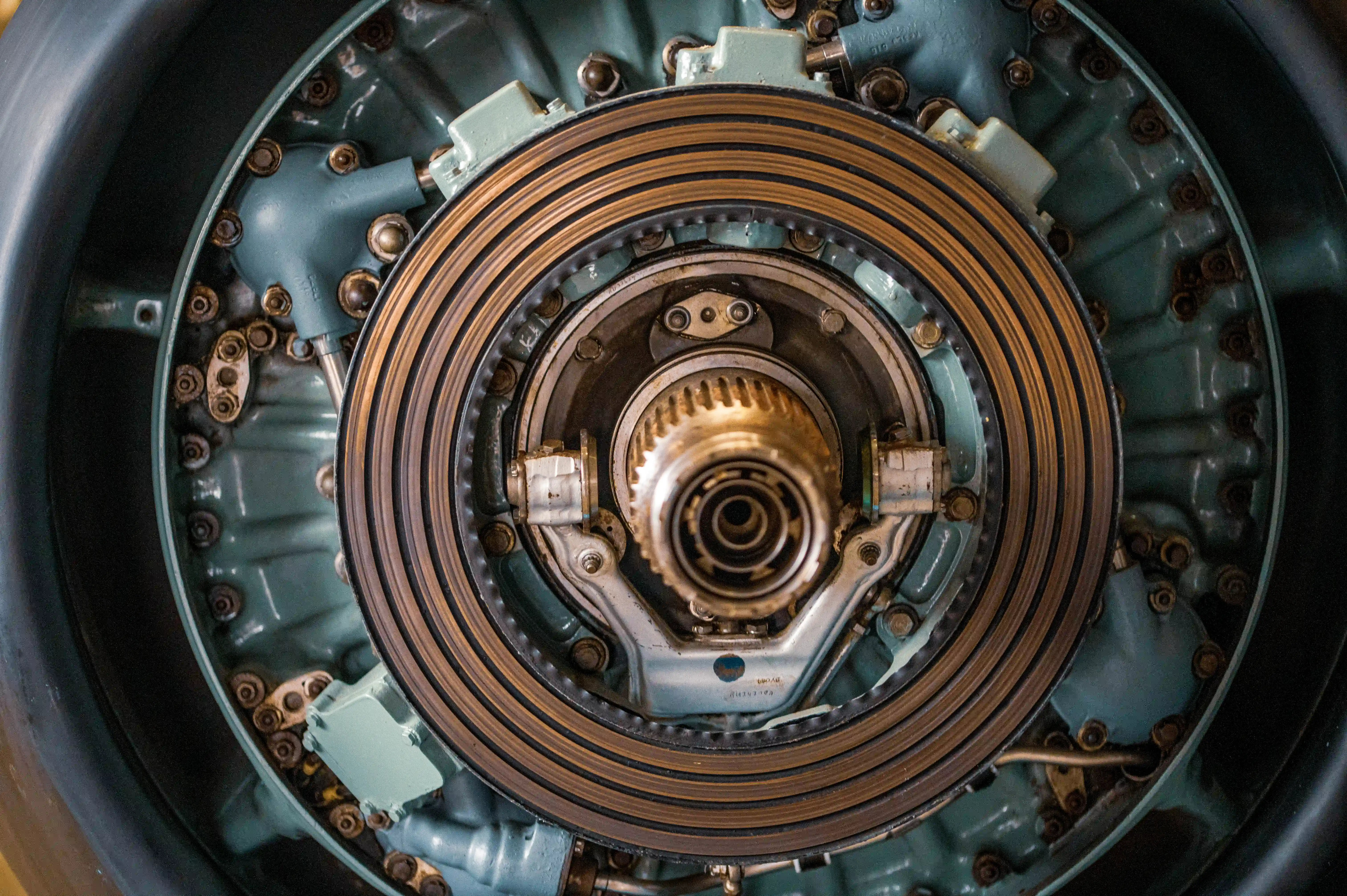 A close-up view of a jet engine turbine assembly, showcasing its concentric rings of turbine blades and central hub. The image highlights the metallic components, bolts, and intricate mechanical details of the turbine