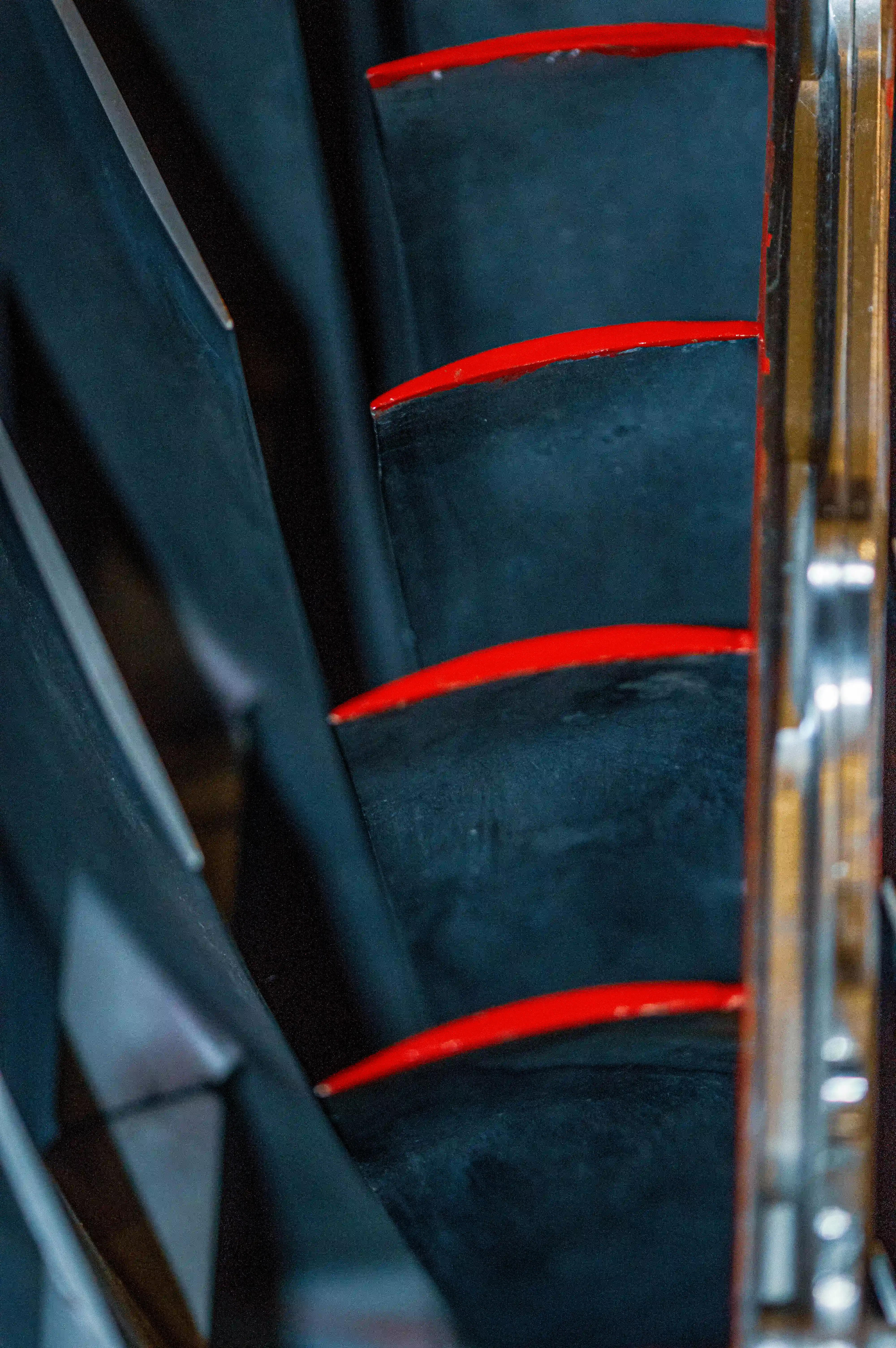 Close-up of dark jet engine fan blades with bright red leading edges, viewed from an angled perspective showing the layered metallic construction.