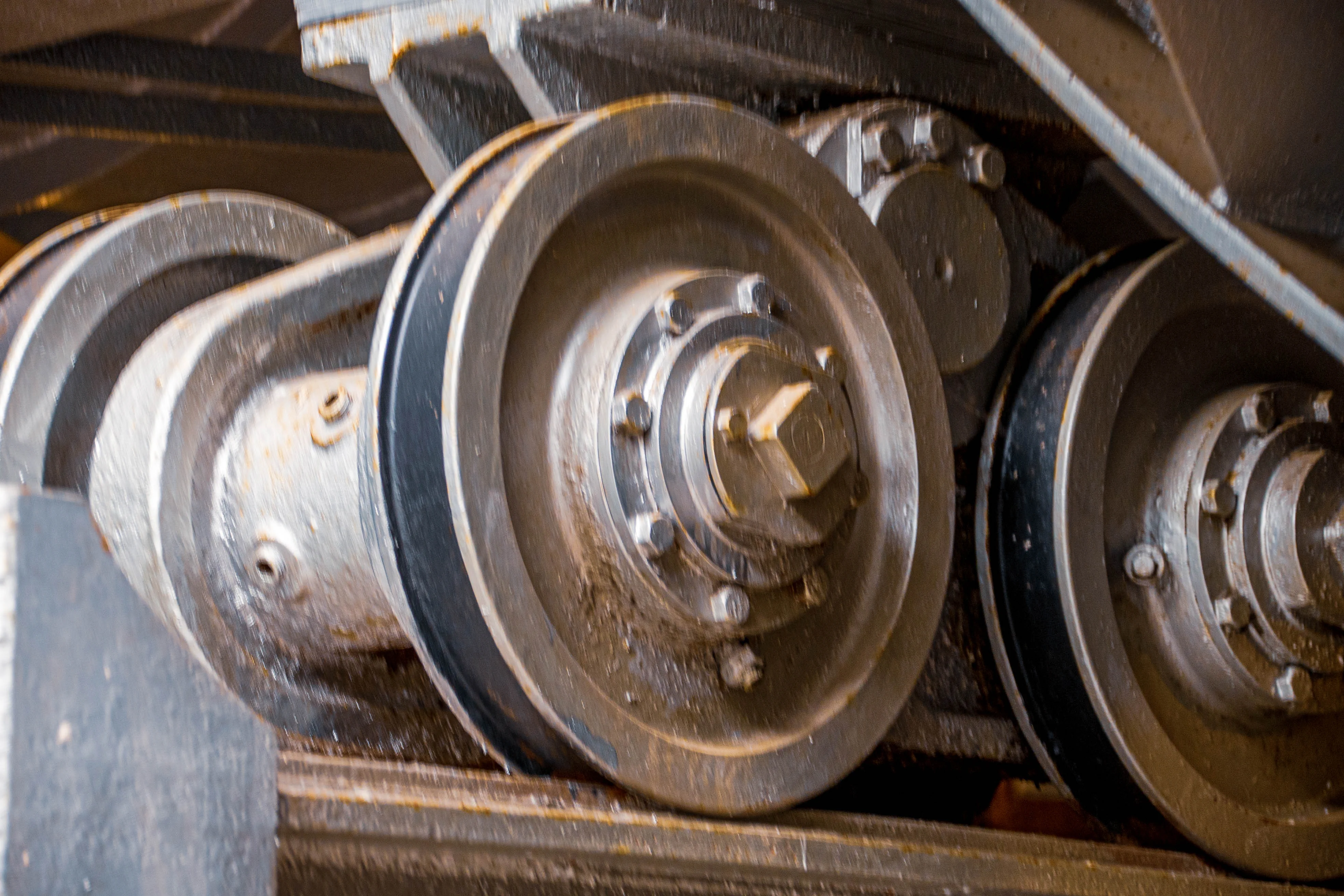 Close-up view of several heavy-duty industrial wheels, each with a black rubber or composite band around its circumference, mounted on metal axes with visible bolts.