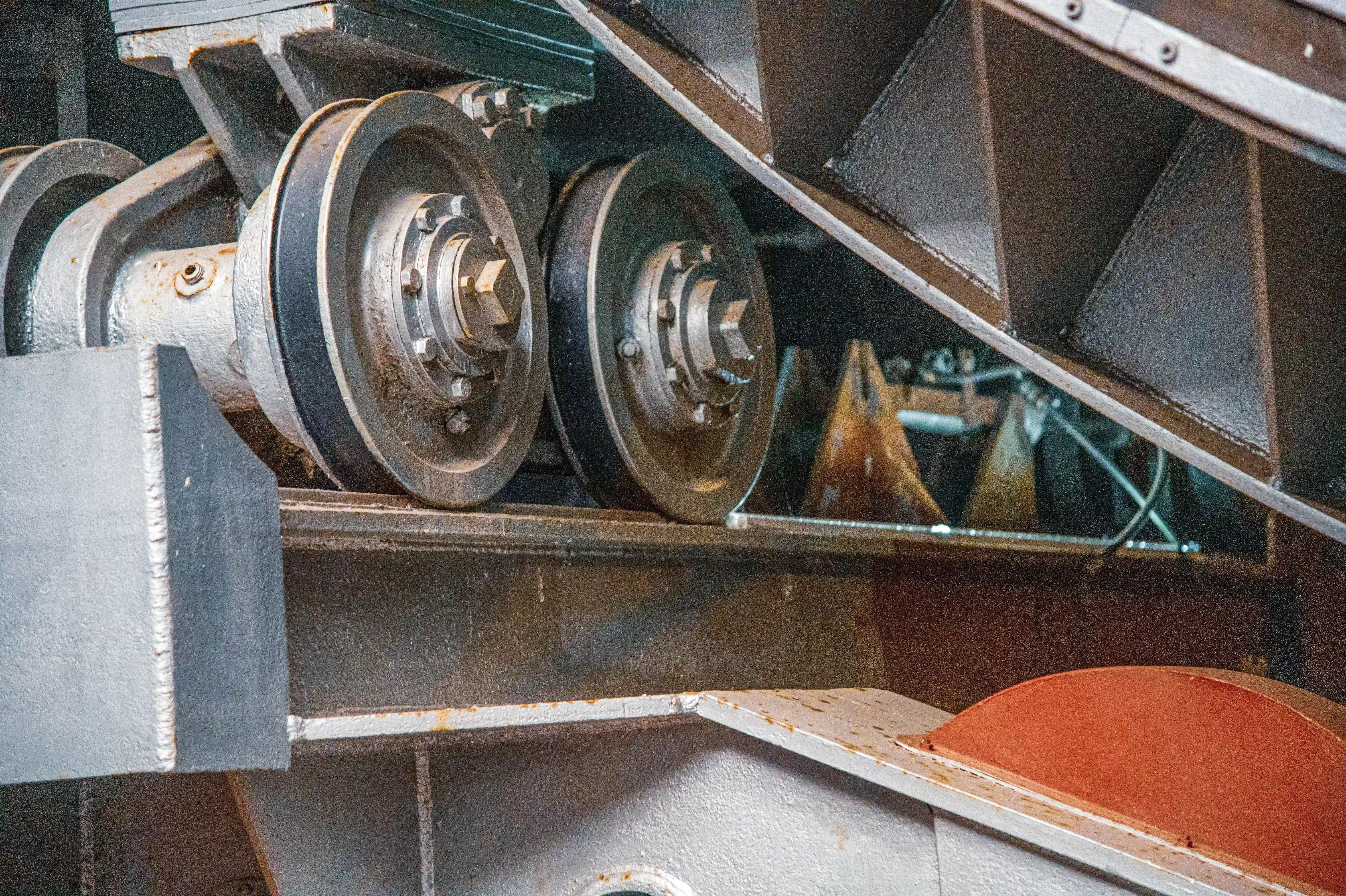 Close-up of heavy industrial wheels and rollers fixed to a steel frame with bolts and nuts.
