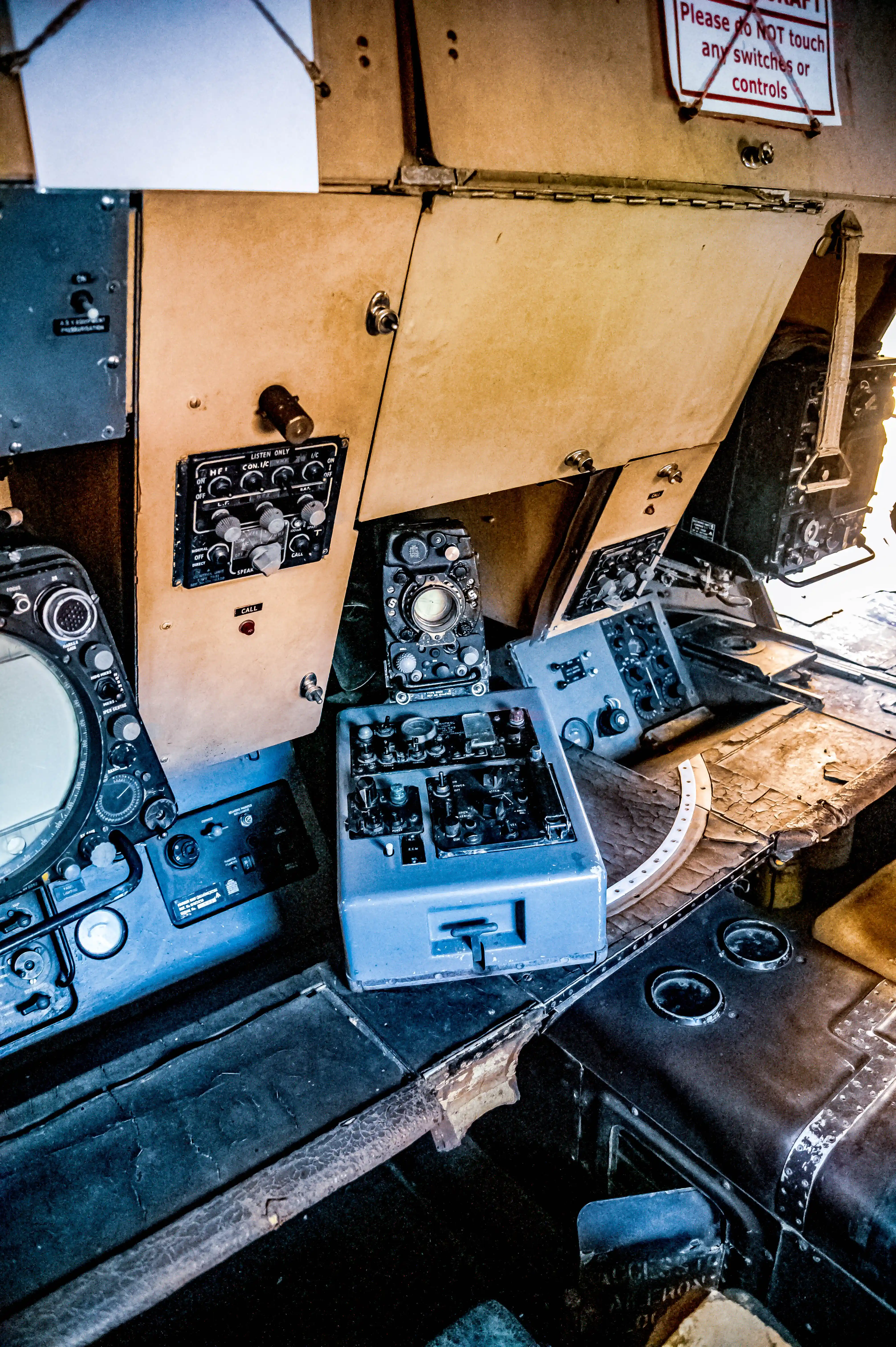 Historic aircraft cockpit with analogue instruments, radar screens, switches and a worn leather navigator’s seat.