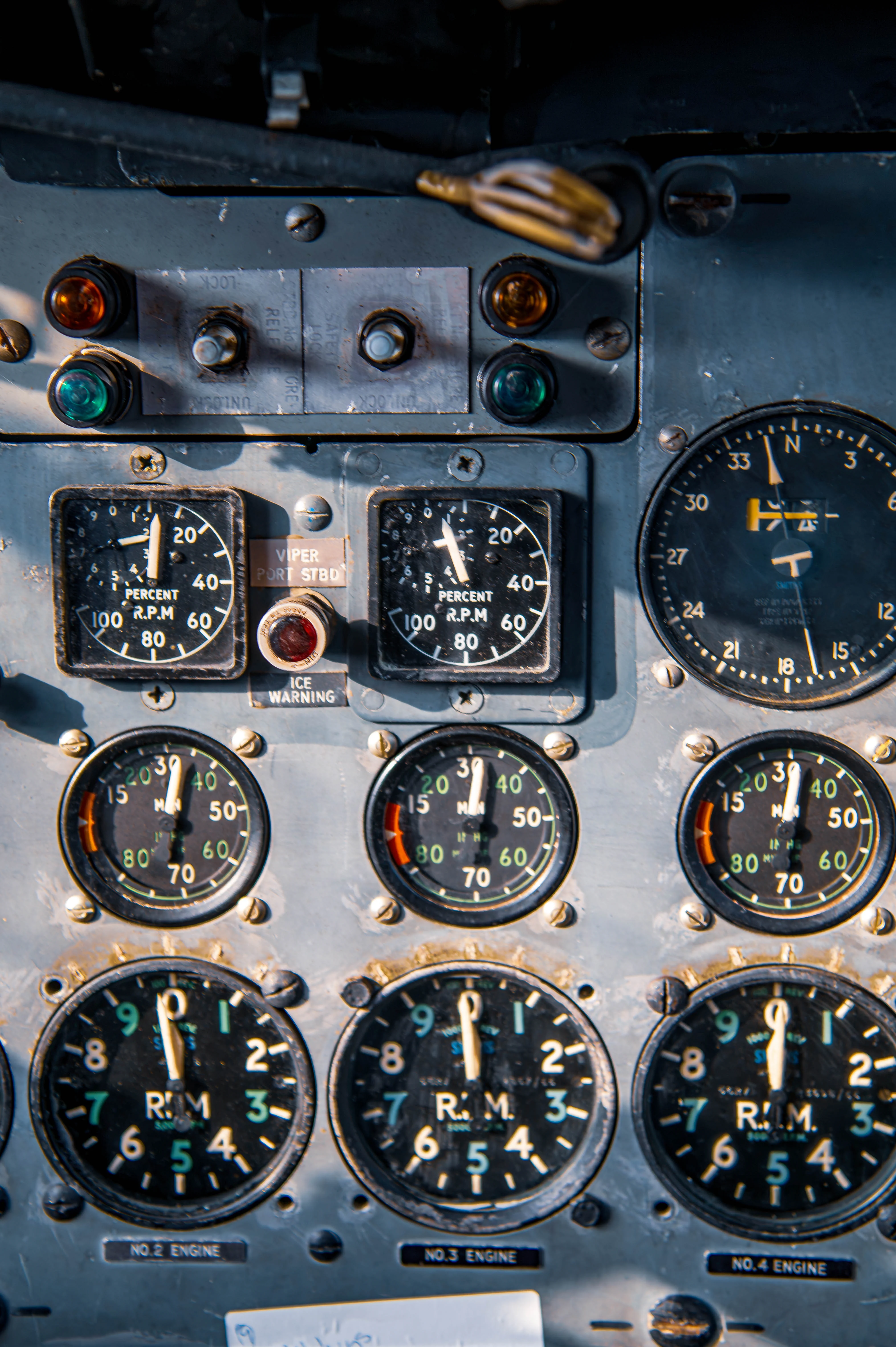 Close-up of an aircraft cockpit instrument panel with analogue gauges, warning lights and multi-engine indicators.