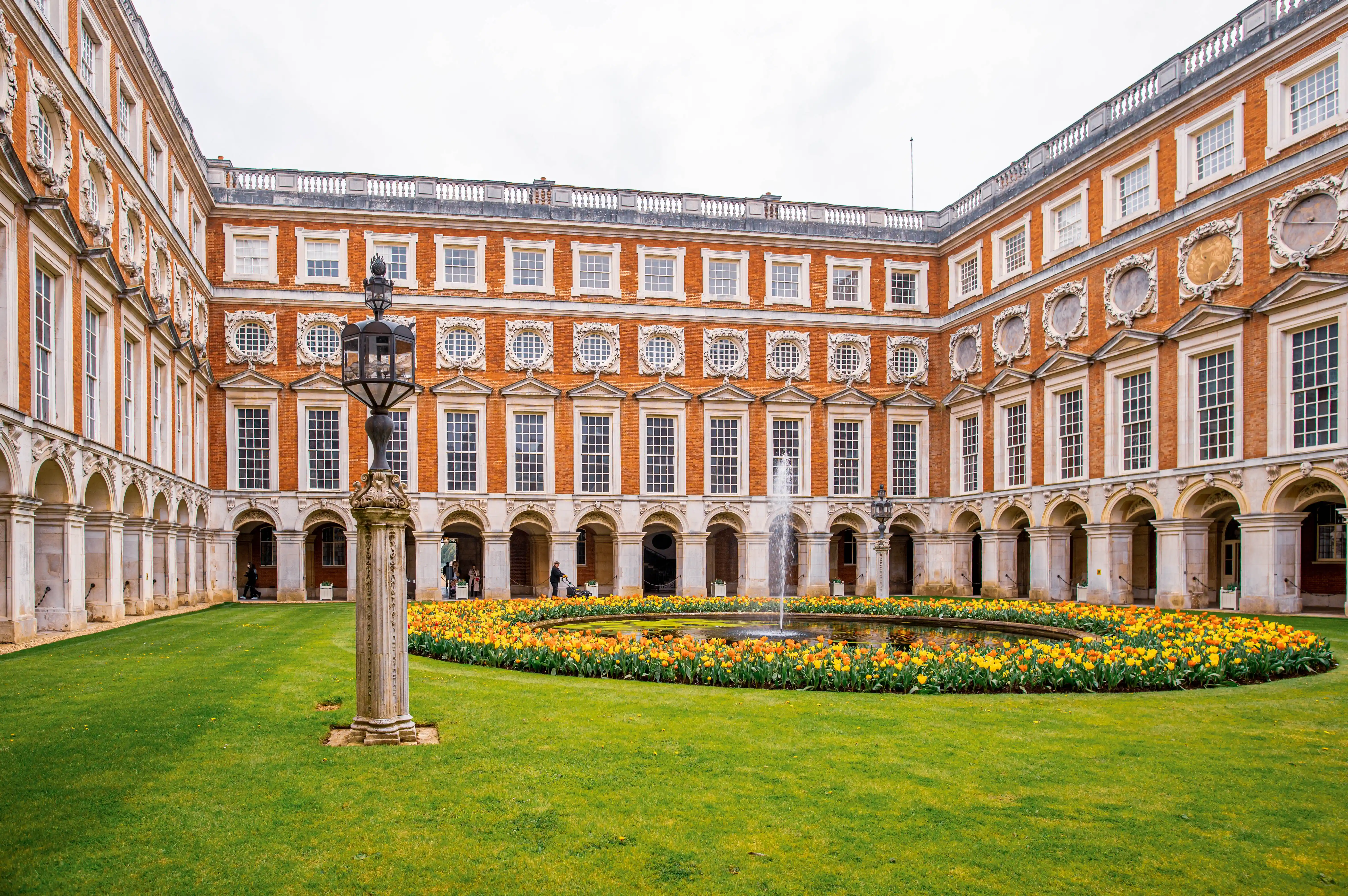 Courtyard of Hampton Court Palace with a fountain and colourful tulip beds.