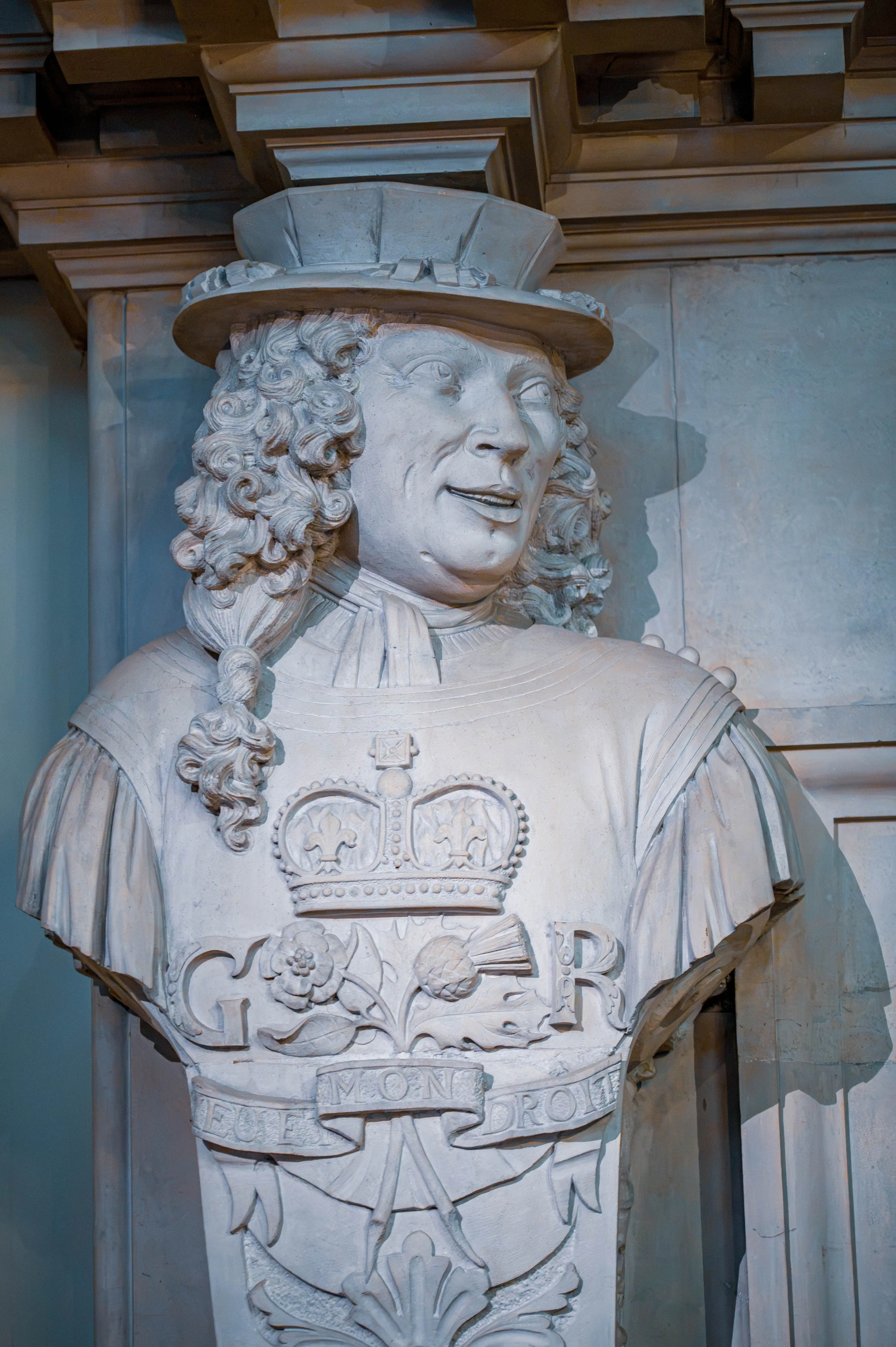 Carved stone bust with crowned “G R” emblem and motto Dieu et mon droit set against a classical wall.