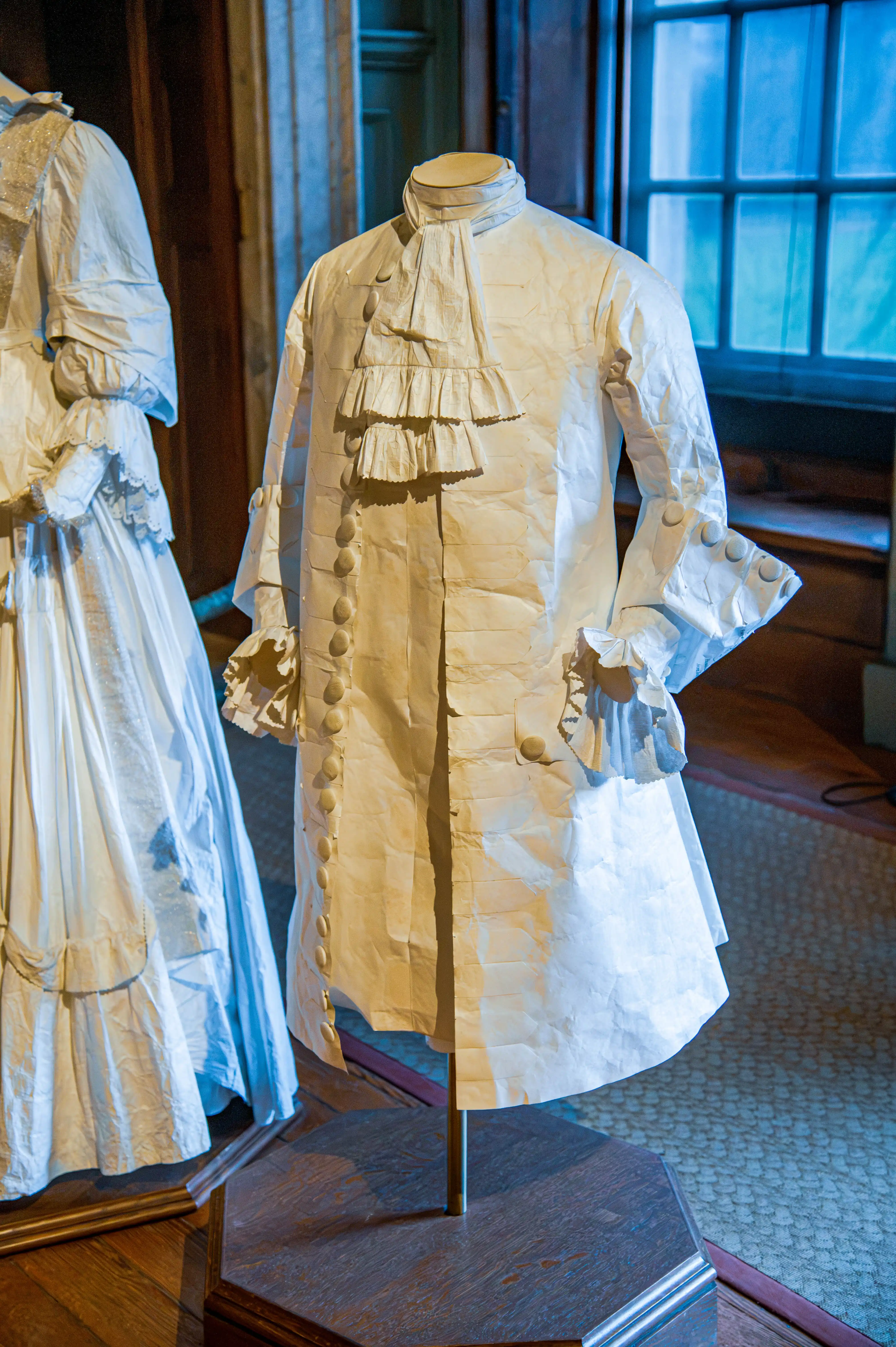 18th-century men’s coat with ruffled cuffs, cravat and decorative buttons displayed on a mannequin.