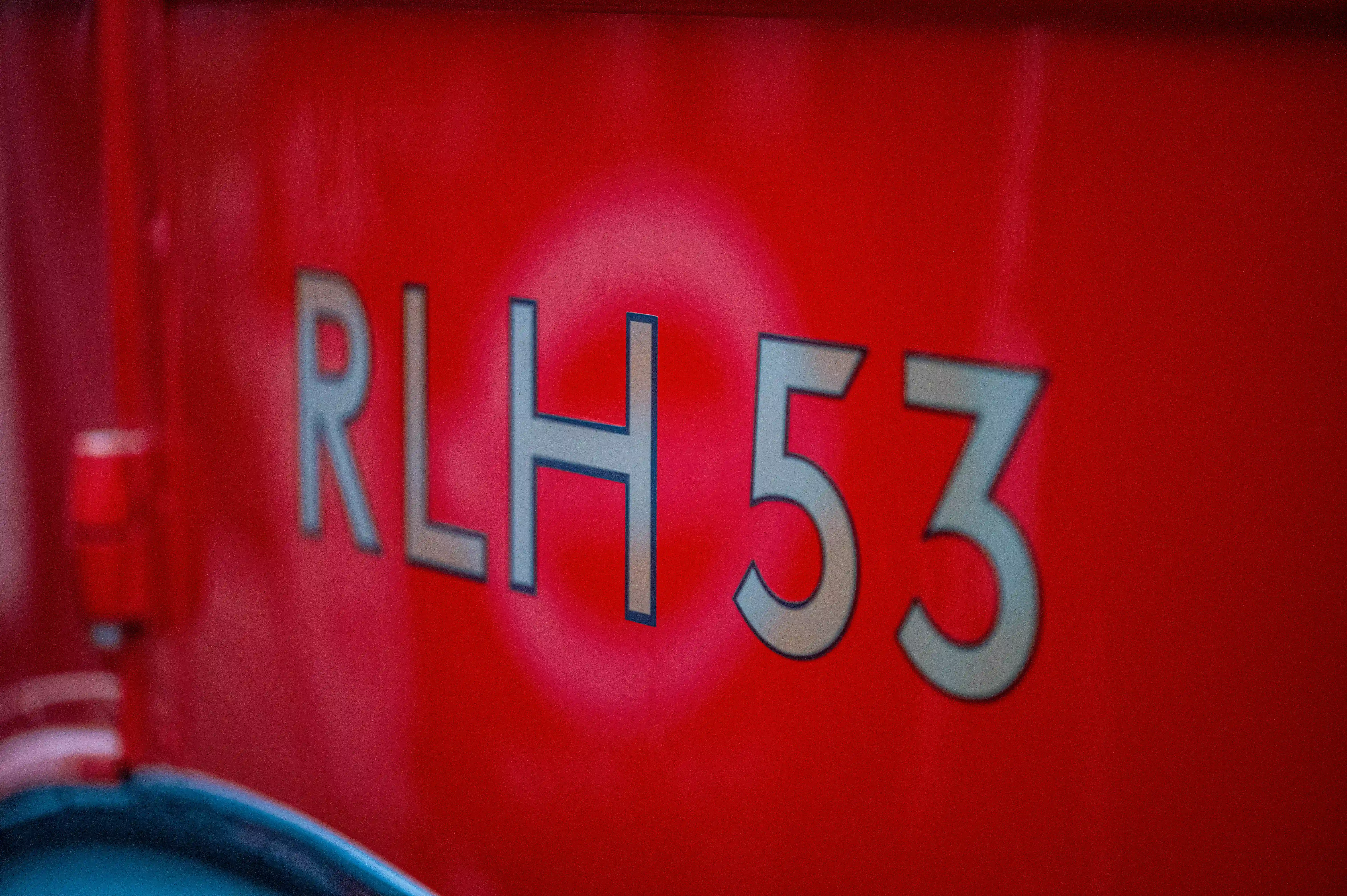 Close-up of the number RLH 53 in silver metallic letters on a red surface.