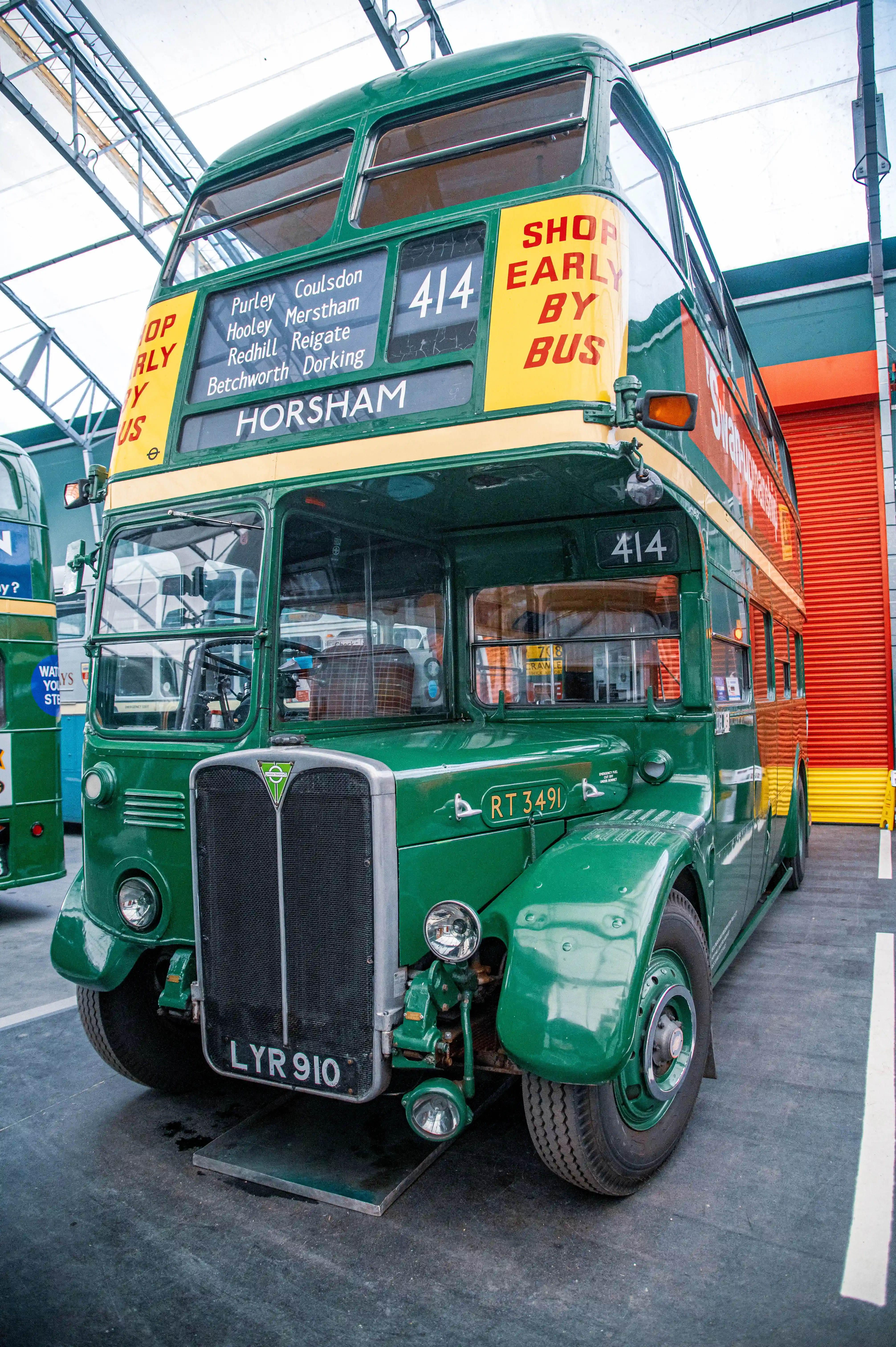 Front view of a classic green London double-decker bus, route 414, with HORSHAM displayed as the destination and SHOP EARLY BY BUS signage.