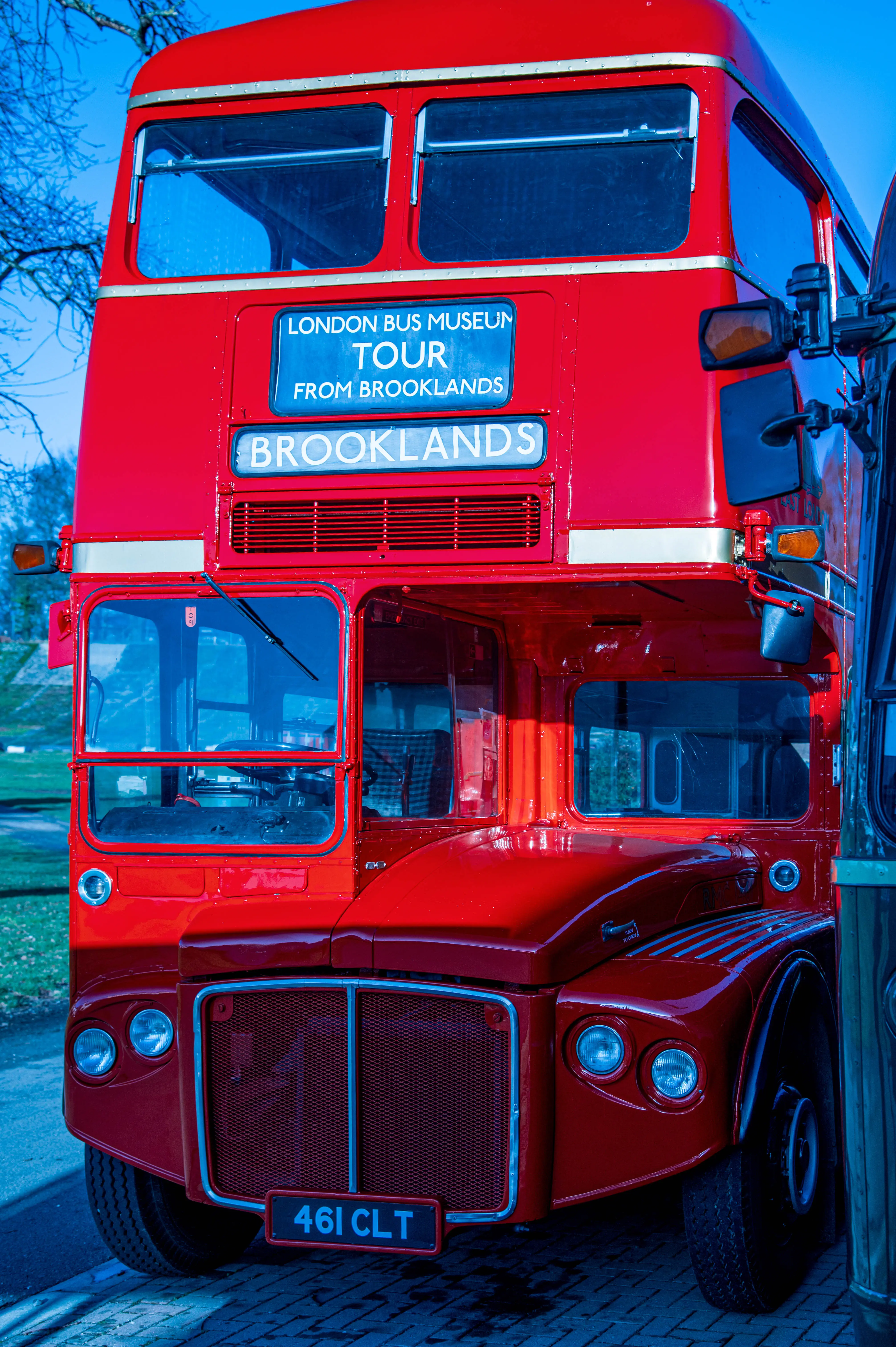 Close-up front view of a bright red vintage London double-decker bus with 'LONDON BUS MUSEUM TOUR FROM BROOKLANDS' displayed on the front.
