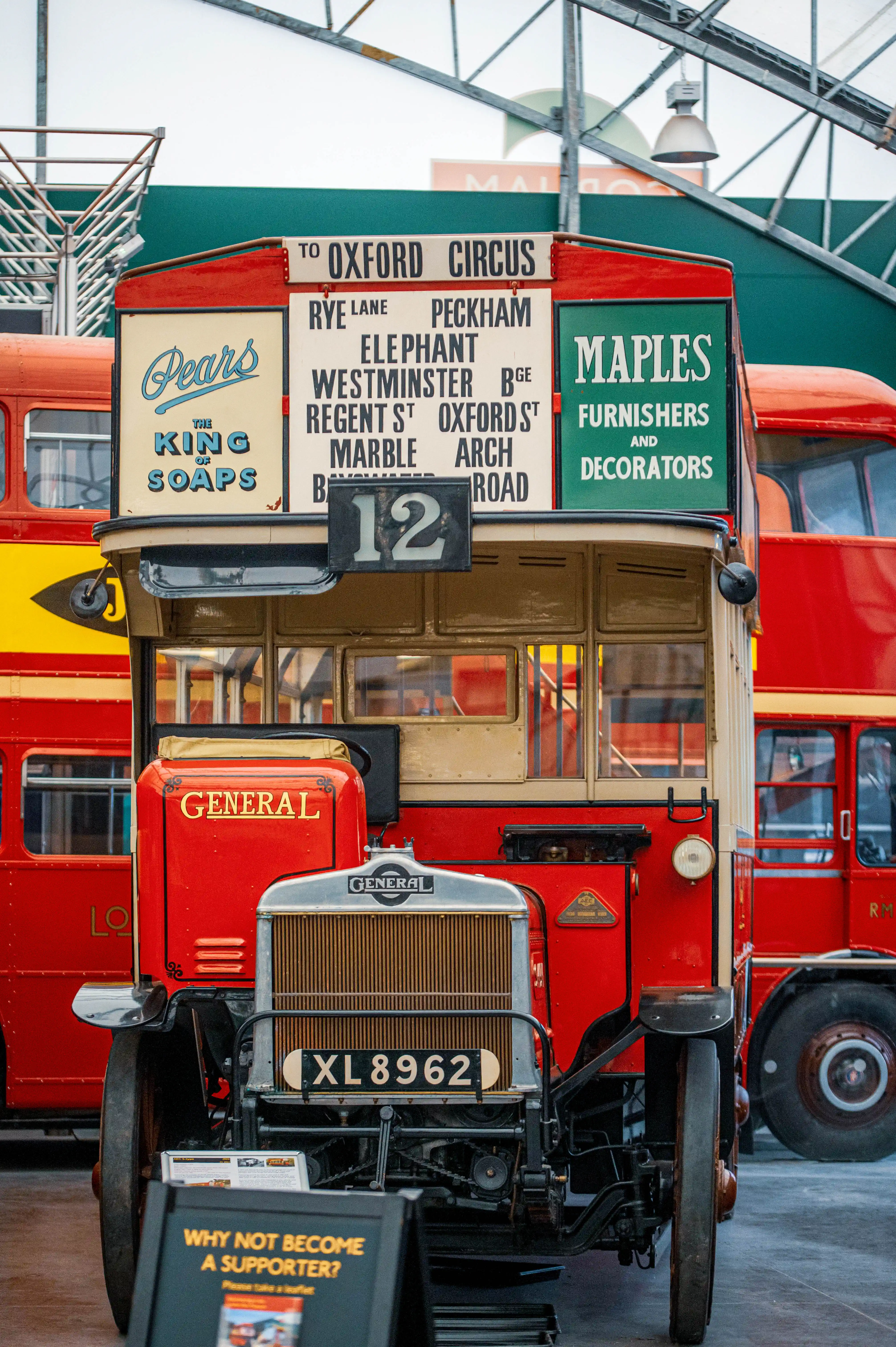 A front-facing view of an old red London double-decker bus with route information displayed above the driver's cabin.