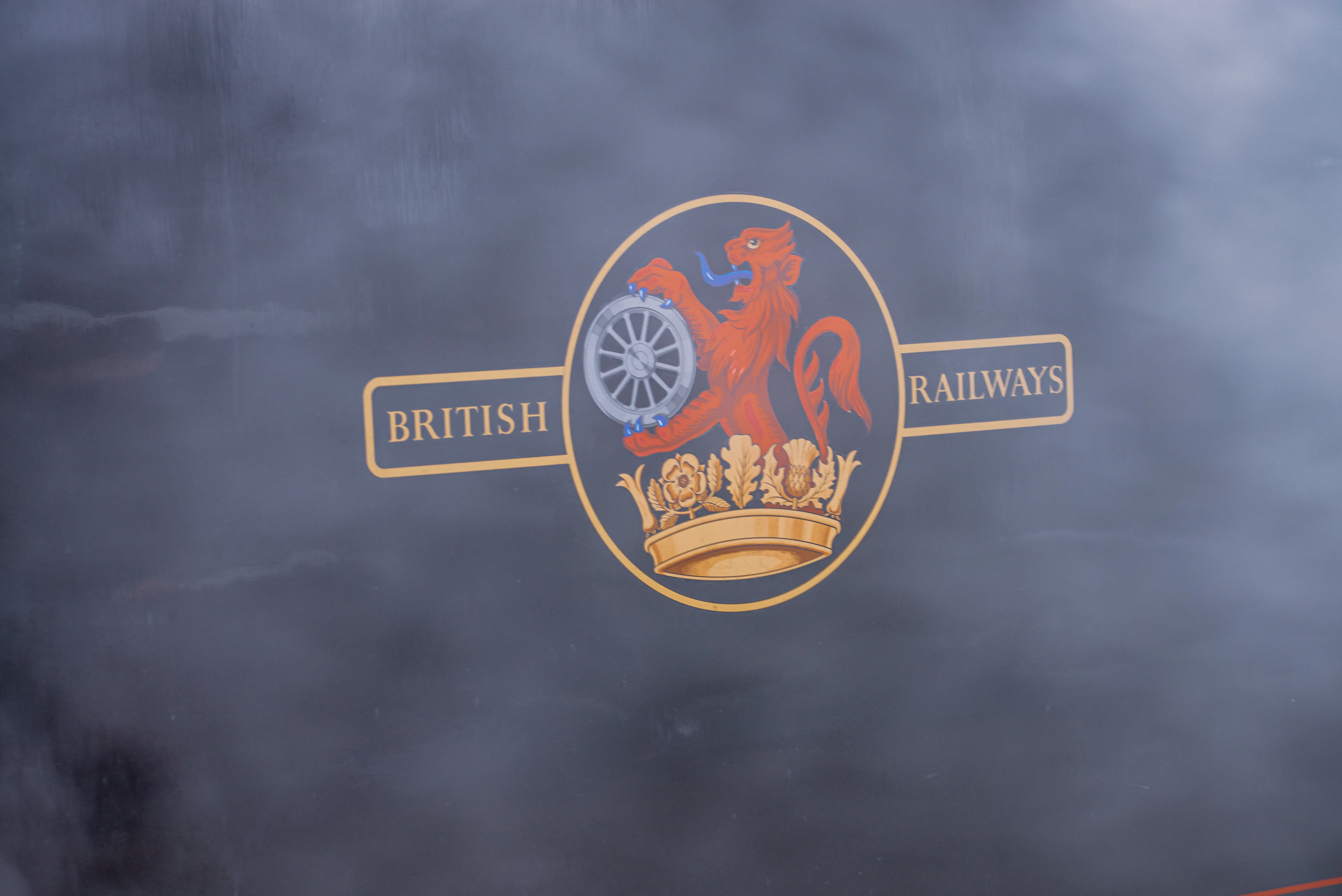 The British Railways logo, featuring a red lion holding a wheel, with a crown below, and the words BRITISH and RAILWAYS on either side, against a dark, slightly smoky background.