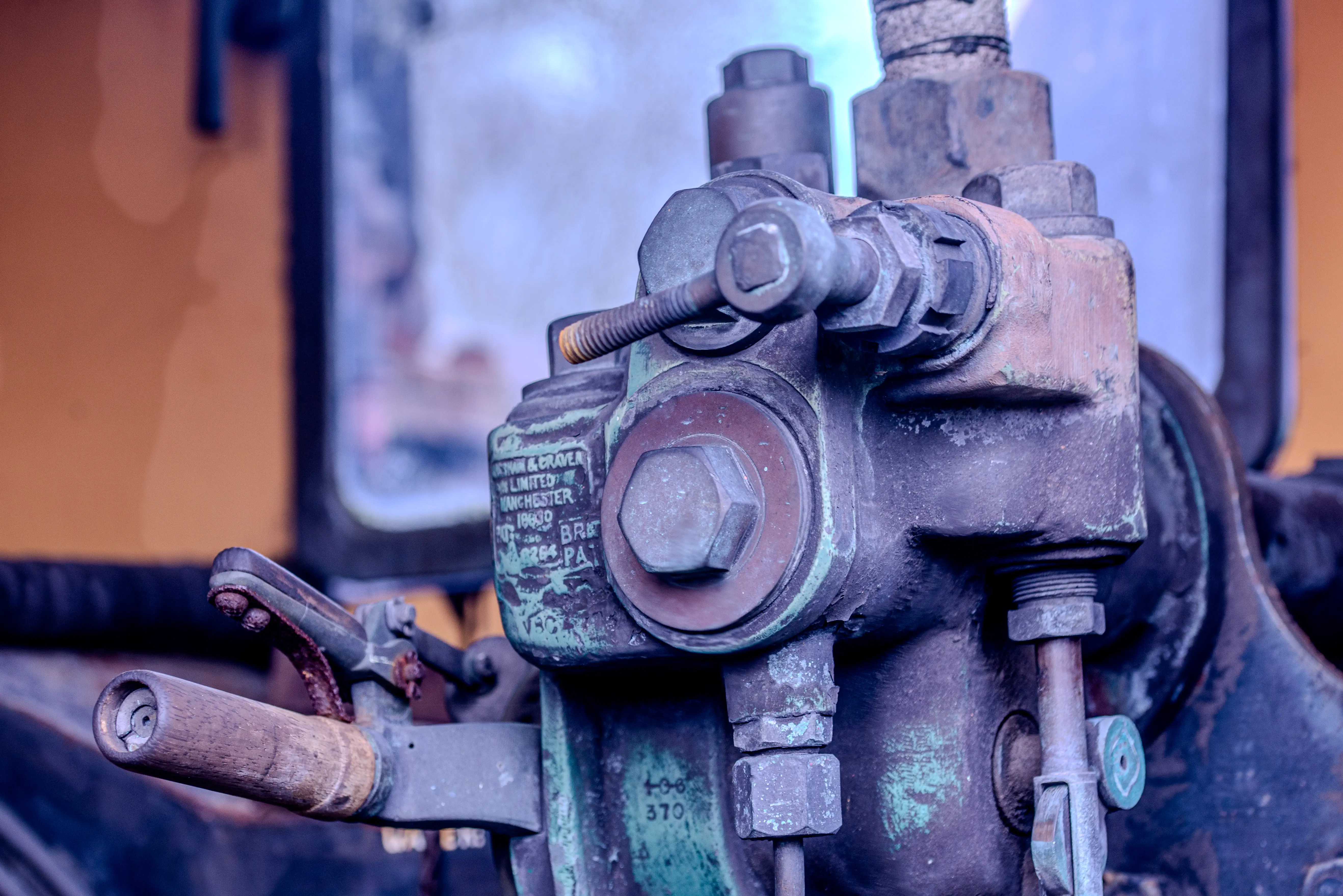 Close-up of a rusty and weathered industrial valve assembly, with a visible nameplate reading 