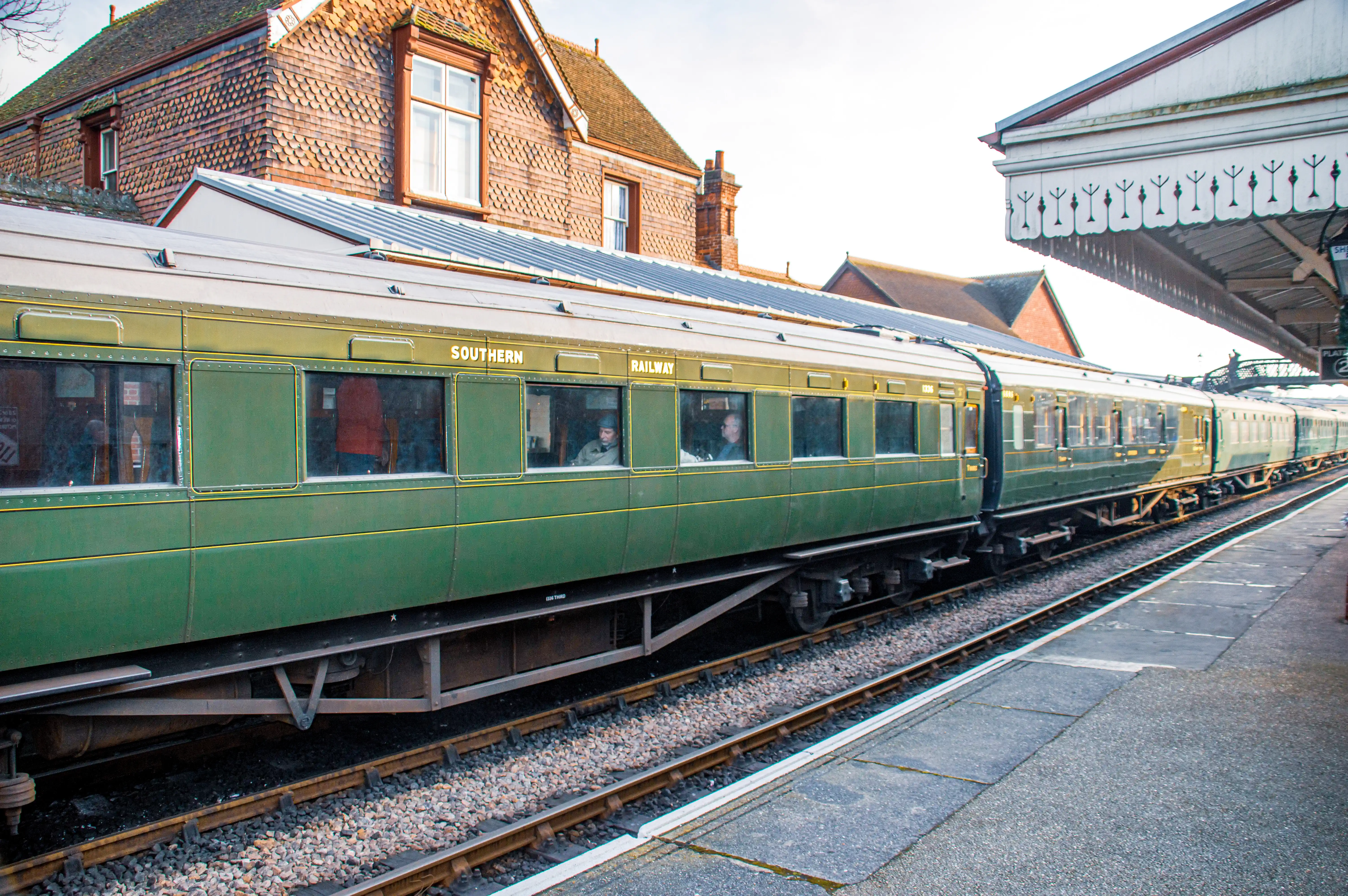 A long, green passenger train with gold trim, identified as 