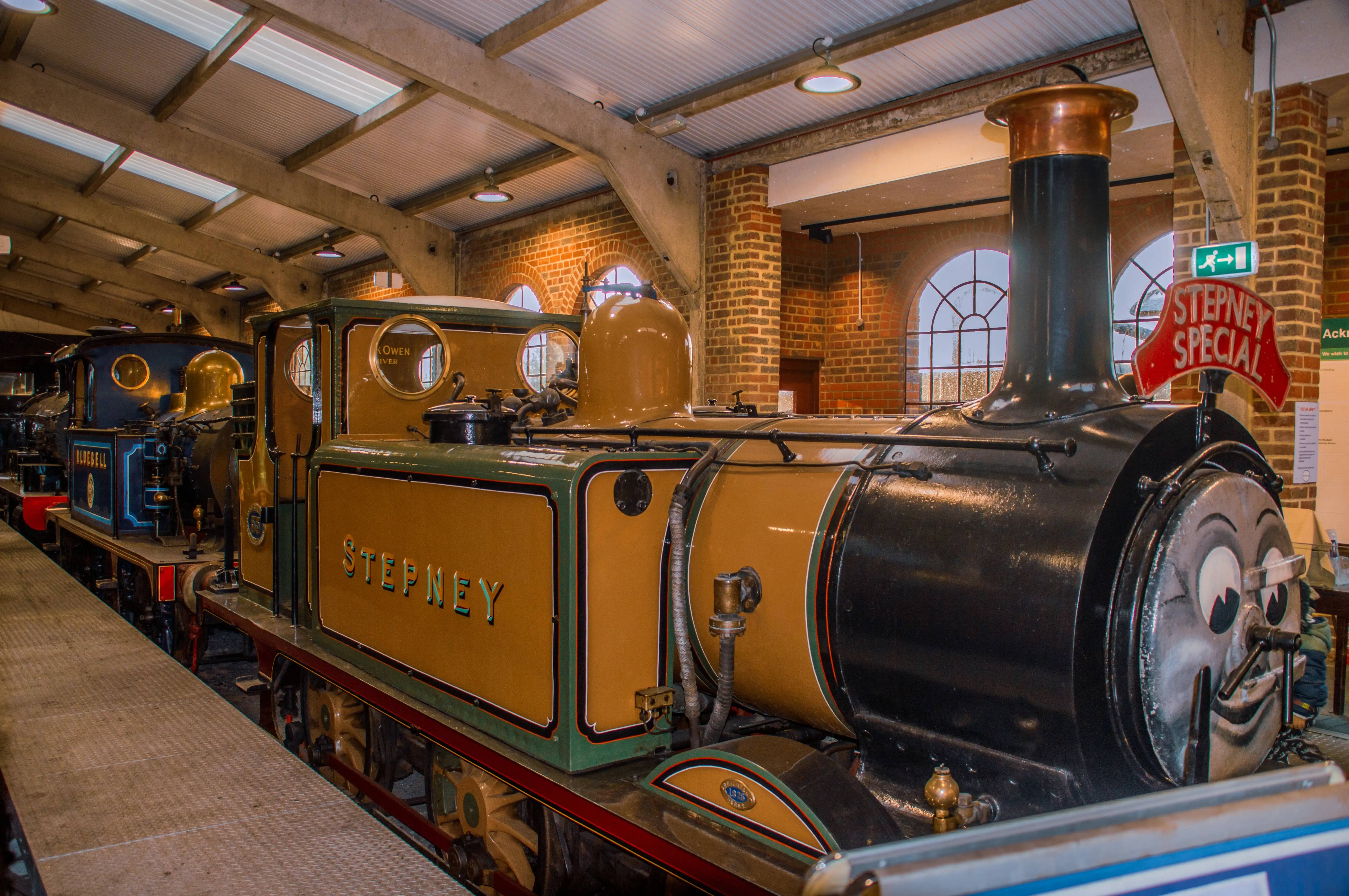 Steam locomotive cab interior showing pressure gauges, brass pipes, valves and a red regulator lever.