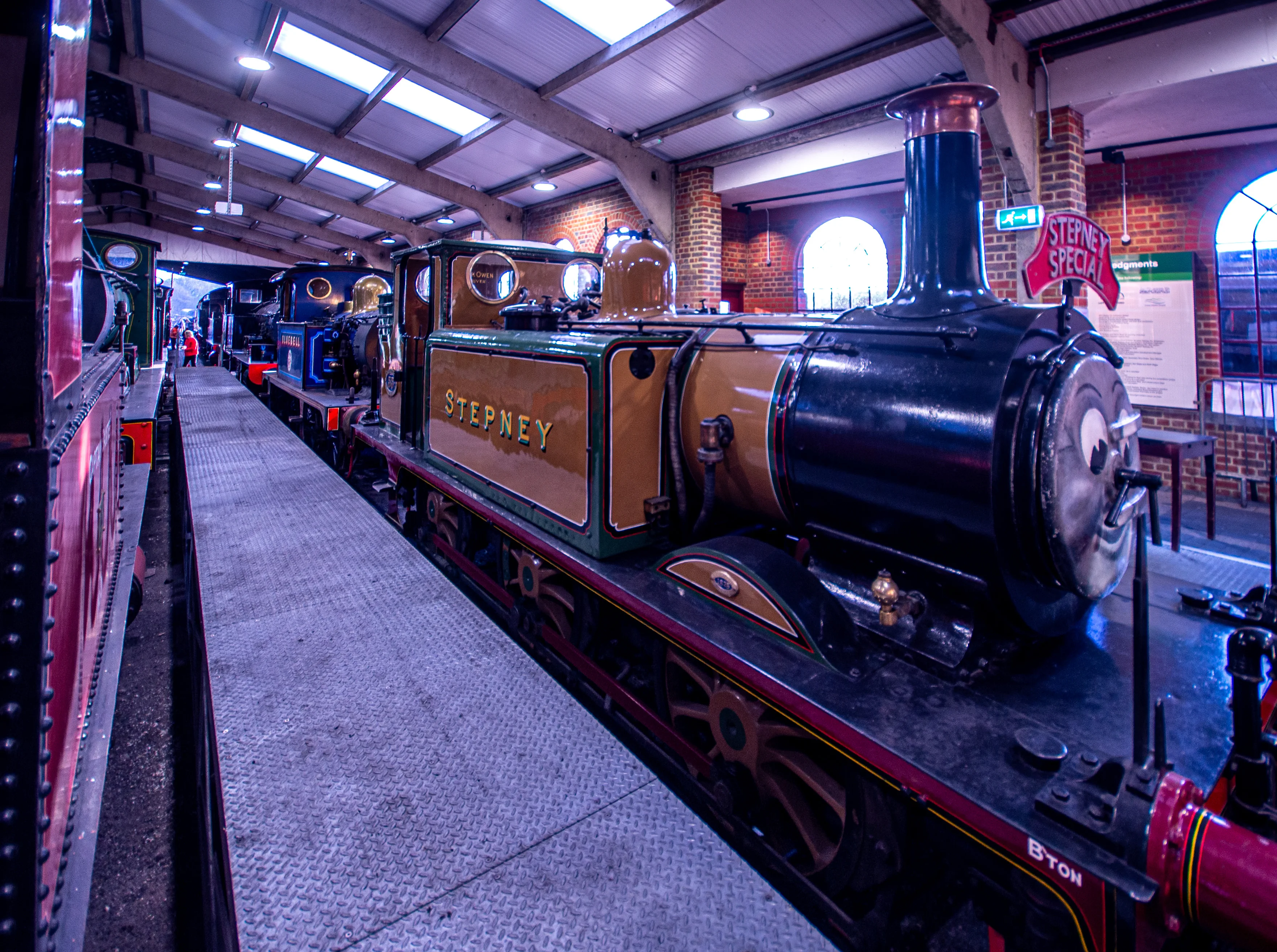Steam locomotive cab interior showing pressure gauges, brass pipes, valves and a red regulator lever.