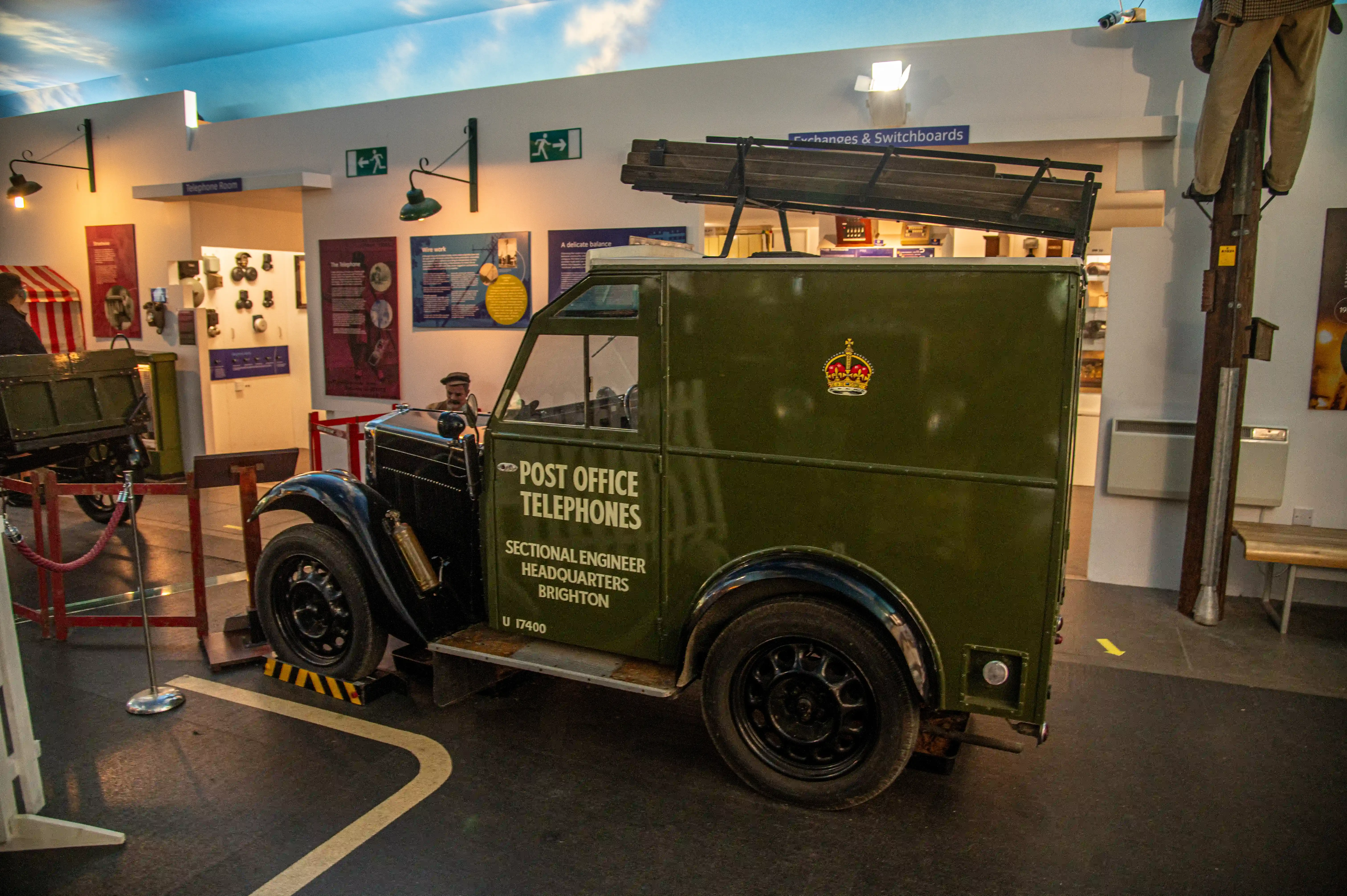 Vintage green Post Office Telephones van in a museum with mannequins showing an engineer and lineman at work.
