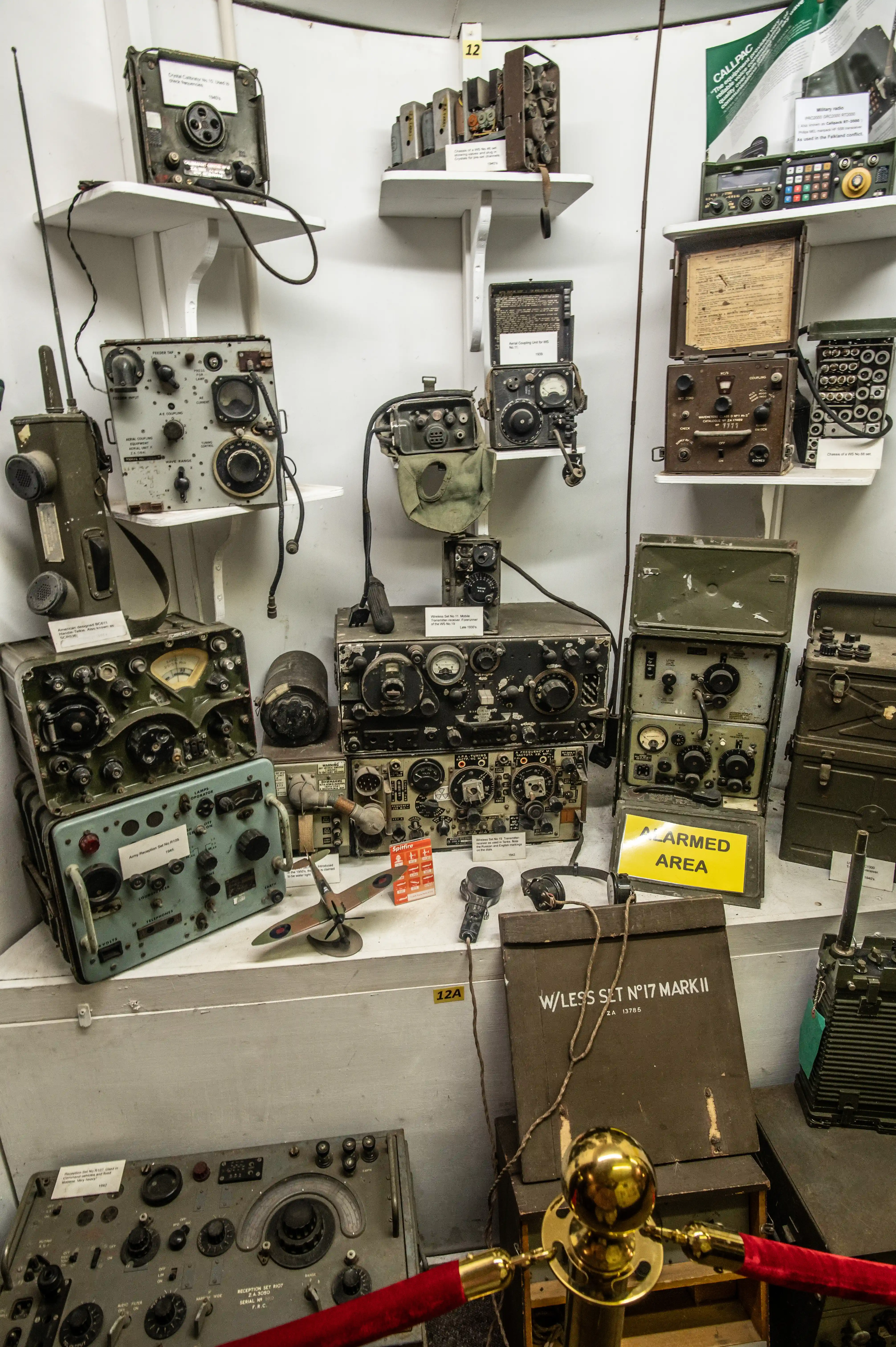 Display of vintage military radio equipment including wireless sets, transceivers, receivers, and labelled units with dials, switches, and meters.