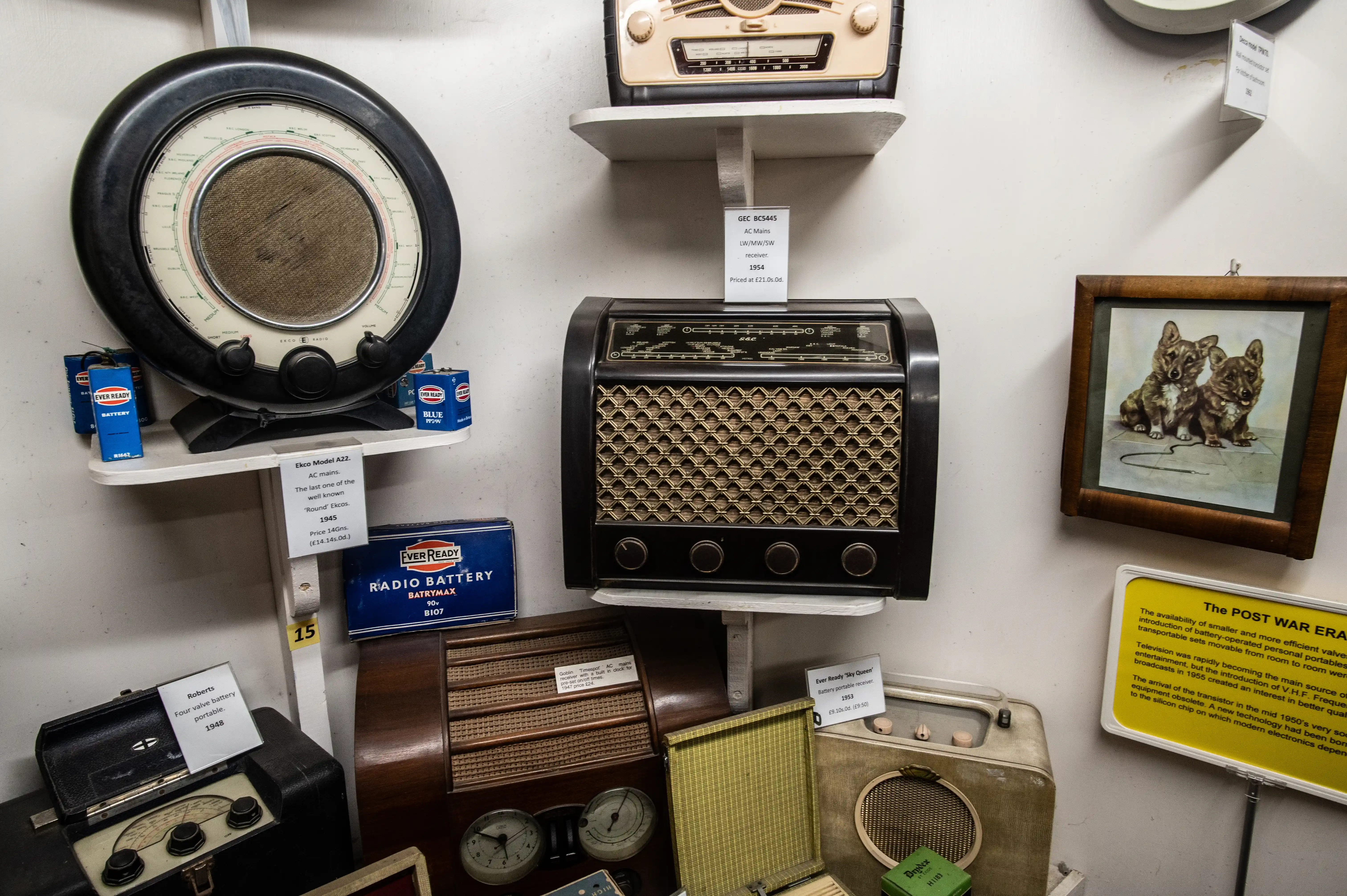 Display of mid-century radios with model labels, Ever Ready batteries, and a yellow “Post War Era” information panel.