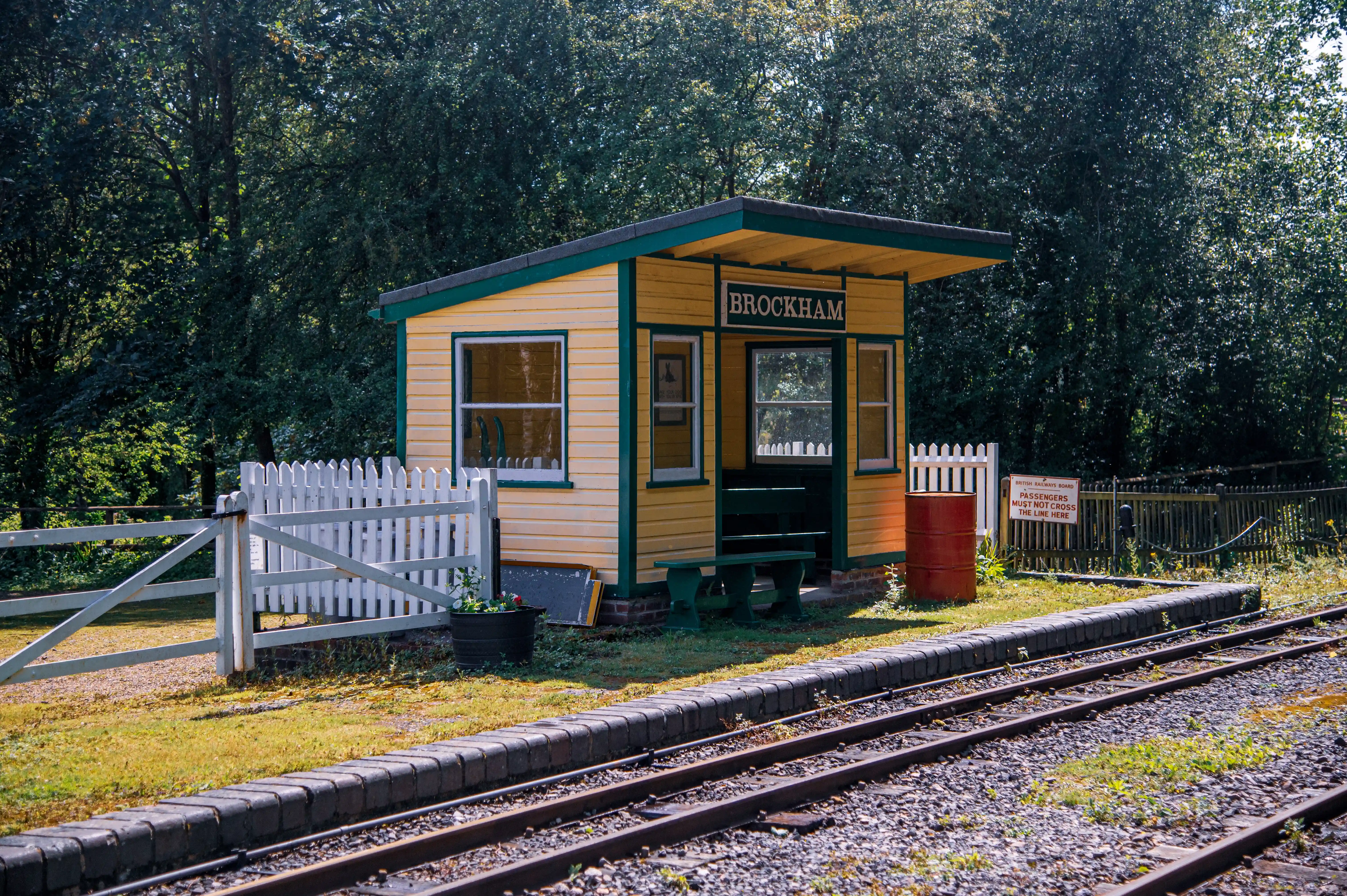 A small, brightly painted wooden railway station building, labelled 