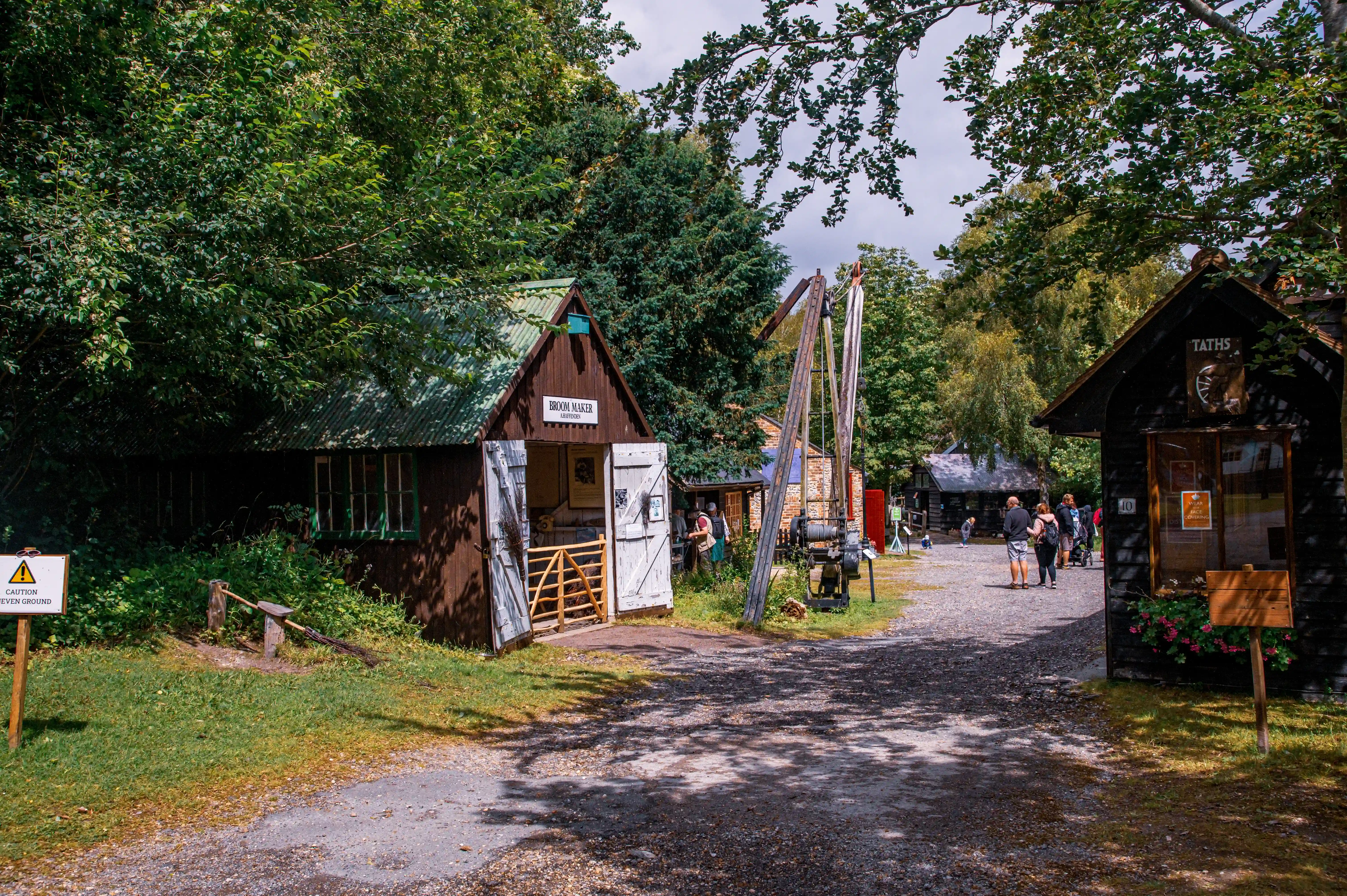 An outdoor view of a village with wooden buildings. The building on the left is labelled 