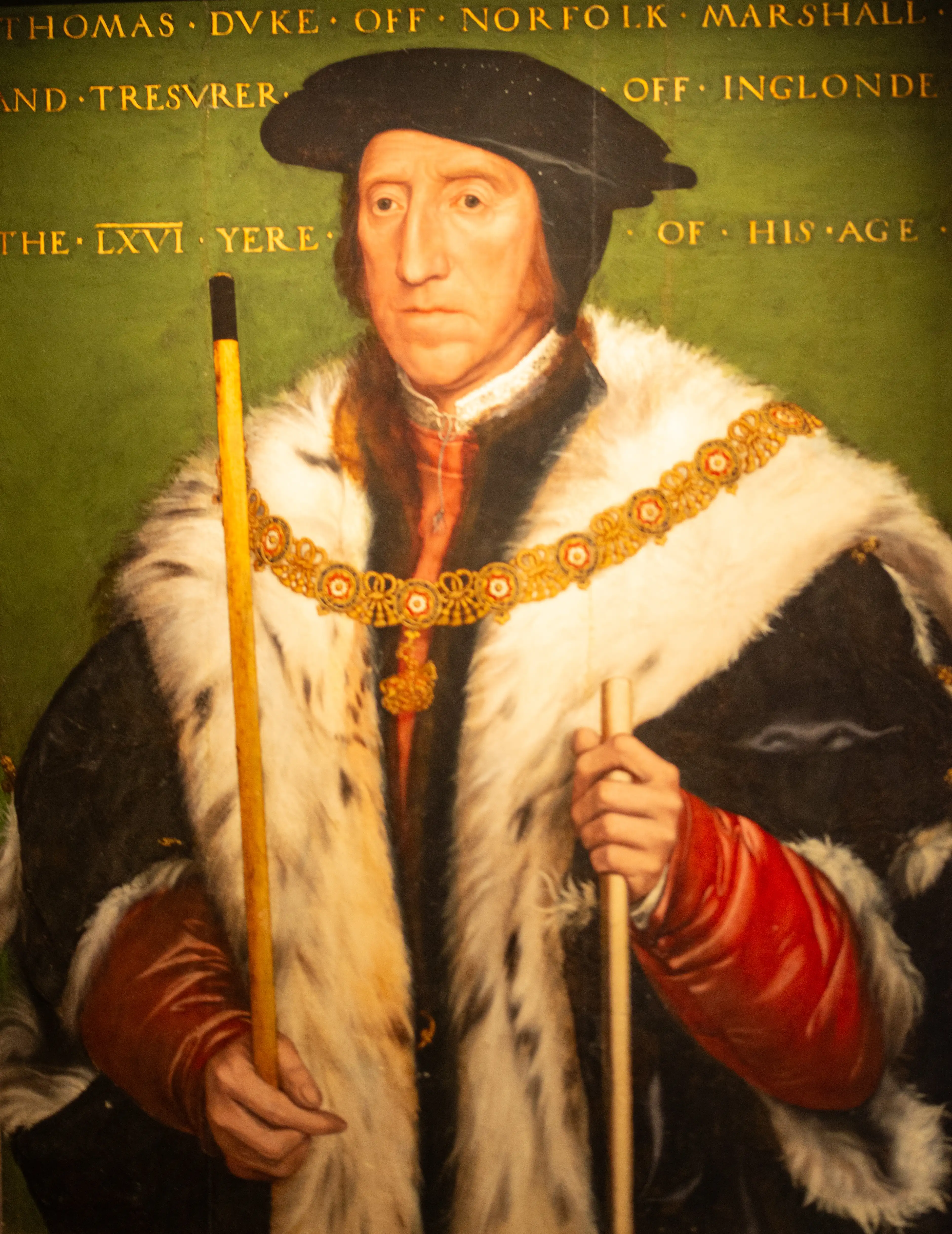 A formal oil painting of a man in 16th-century attire, identified by inscriptions as Thomas Howard, 3rd Duke of Norfolk. He wears a black hat, a fur-trimmed robe, and a gold chain, and holds two staffs.