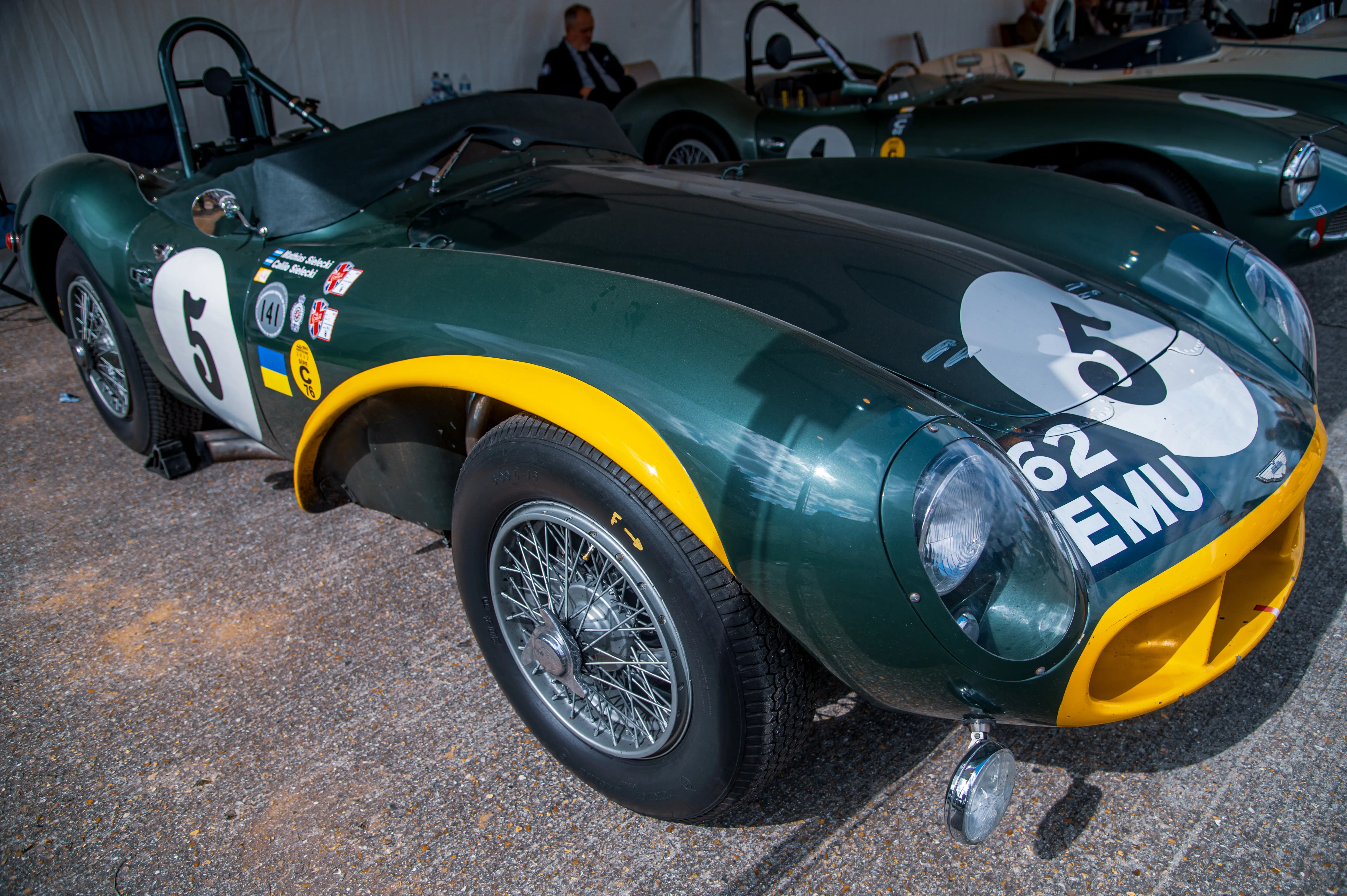 A close-up view of a vintage dark green racing car with yellow trim and a prominent white number 