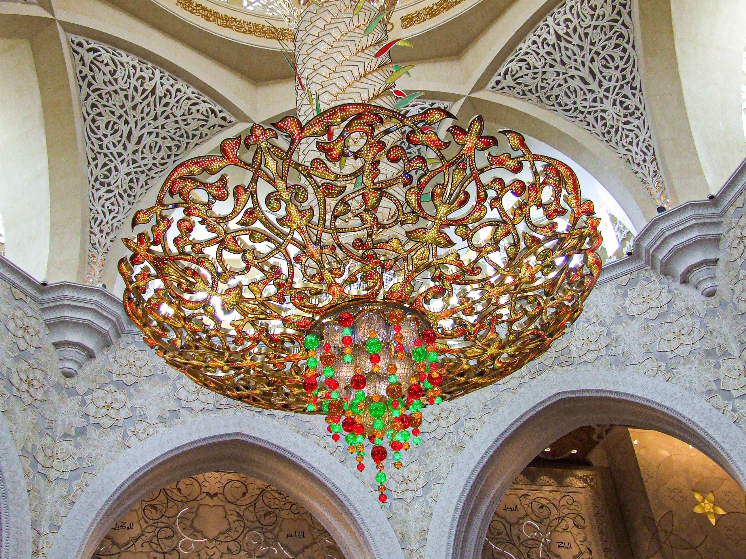 The chandelier features a mix of gold, red, and green colors with elaborate patterns