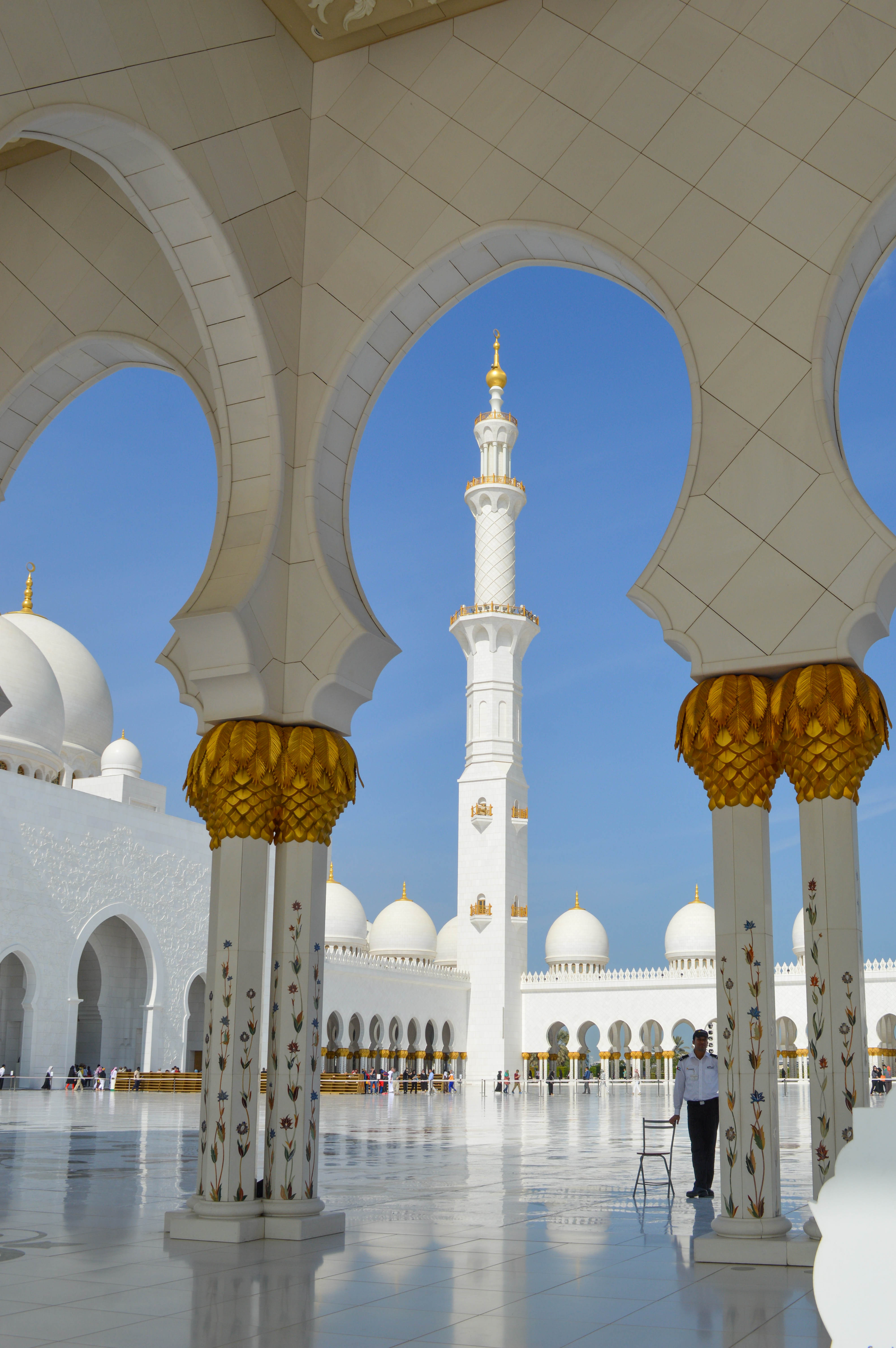  A tall minaret is visible in the background, and the courtyard is spacious with reflective marble floors